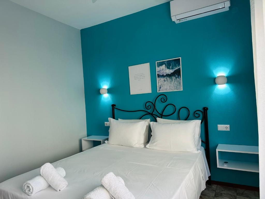 a blue bedroom with a bed with white pillows at W Pearl Suite in Nea Peramos