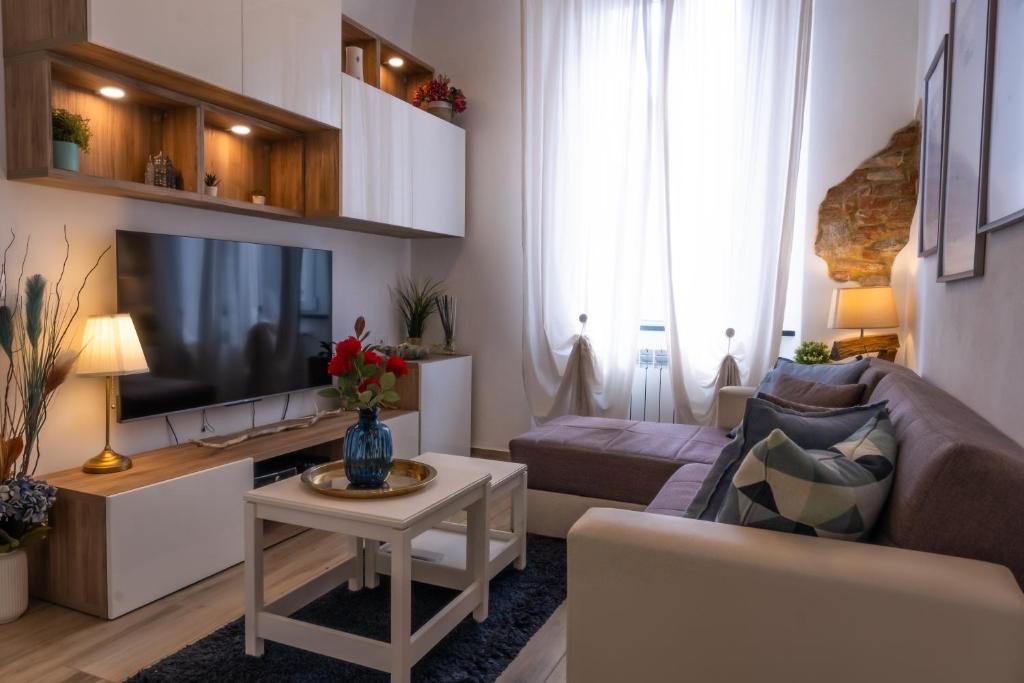 sala de estar con sofá y TV en Dimora Pietra Blu, en Pisa
