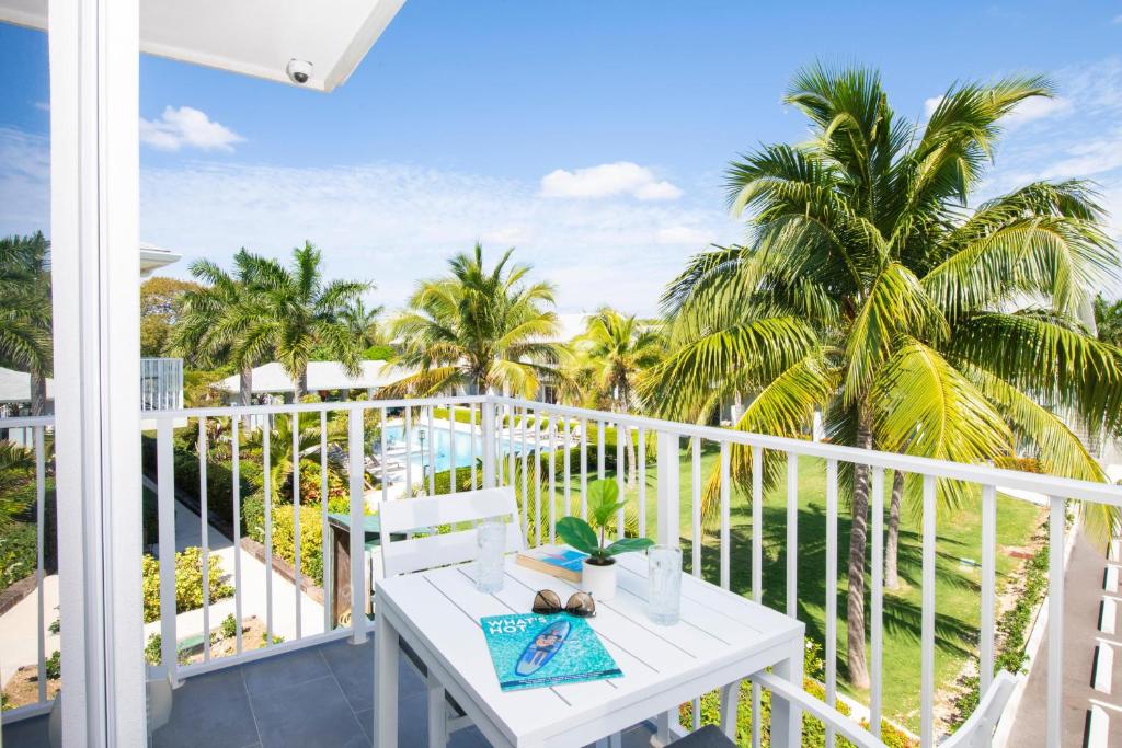 a white balcony with a table and palm trees at Summertime Suites #54 in West Bay