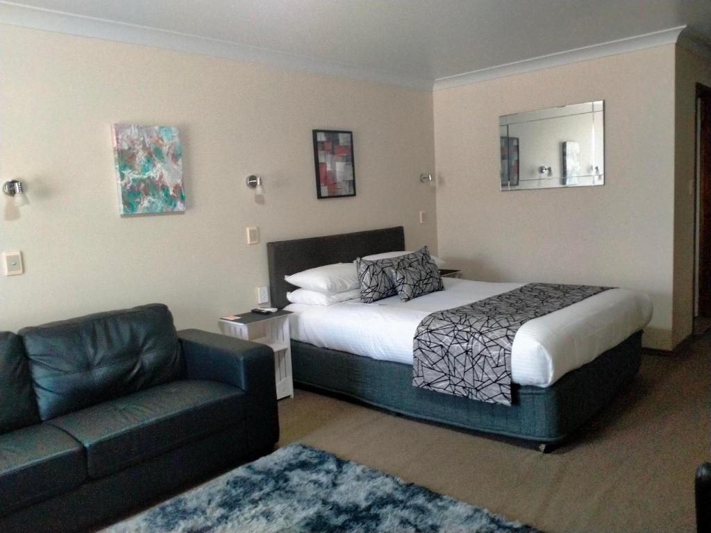 a hotel room with a bed and a couch at Sandstock Motor Inn Armidale in Armidale