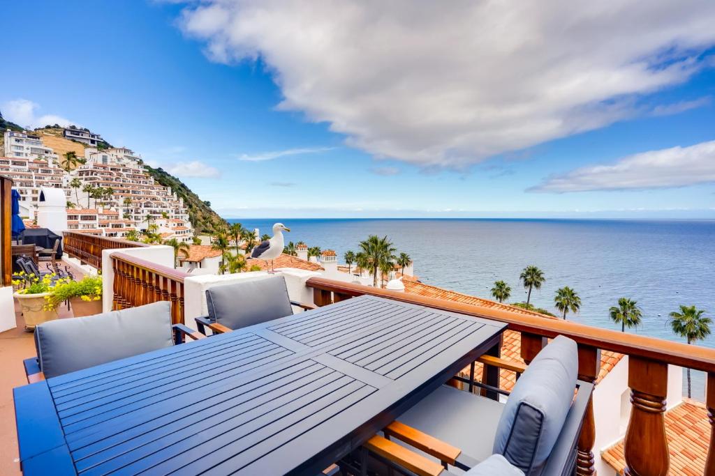 a balcony with a table and chairs and the ocean at Bright Catalina Island Condo with Ocean Views! in Avalon