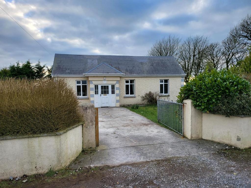 een wit huis met een poort en een oprit bij Peaceful Farm Cottage in Menlough near Mountbellew, Ballinasloe, Athlone & Galway in Galway