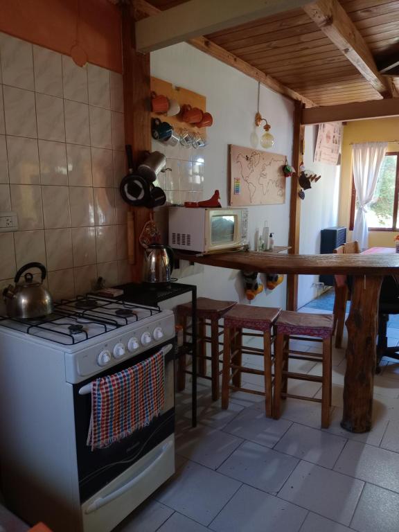 uma cozinha com um fogão e um balcão com uma mesa em Mi casita.envla em Villa La Angostura