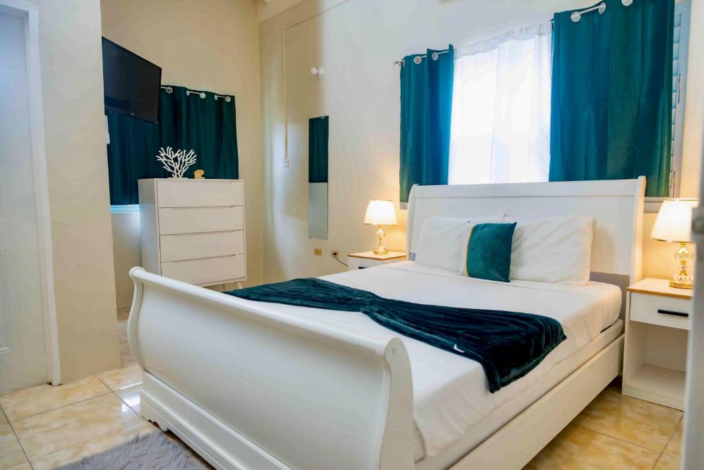um quarto com uma cama branca e cortinas azuis em Emerald inn at runaway bay em Runaway Bay