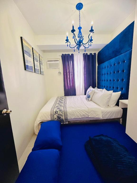 Un dormitorio con una cama azul y una lámpara de araña. en CasadeIsabel: Elegant 2BR n Cebu/Washing/Netflix en Cebú