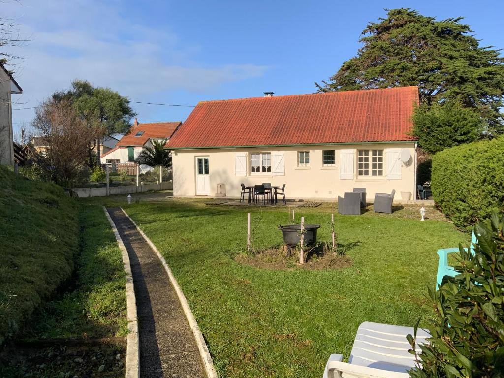une maison blanche avec un toit rouge dans une cour dans l'établissement LES BAINS, à Barneville-Carteret