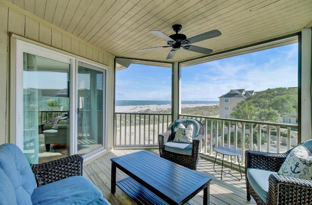 a screened in porch with a couch and a ceiling fan at 304 E Port by AvantStay Rooftop Deck Close to Beach in Isle of Palms