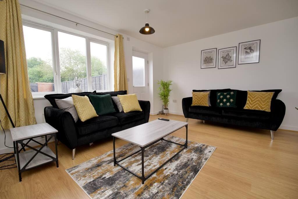 uma sala de estar com um sofá preto e uma mesa em 2Bed Haven - Coventry's Hidden Gem With Free Parking, Sky TV & Netflix em Coventry