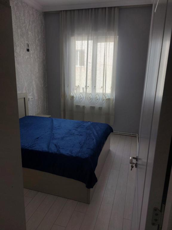Un dormitorio con una cama azul y una ventana en House on Dolidze, en Rustavi