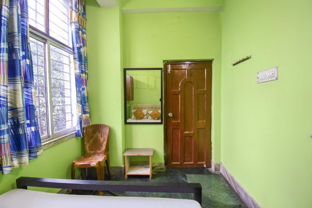 a room with a bed and a door and a chair at OYO Petals Residency in Nager Bazaar