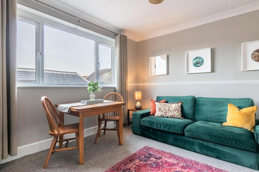 a living room with a green couch and a table at Sweet Ness River Flat, Inverness City in Inverness