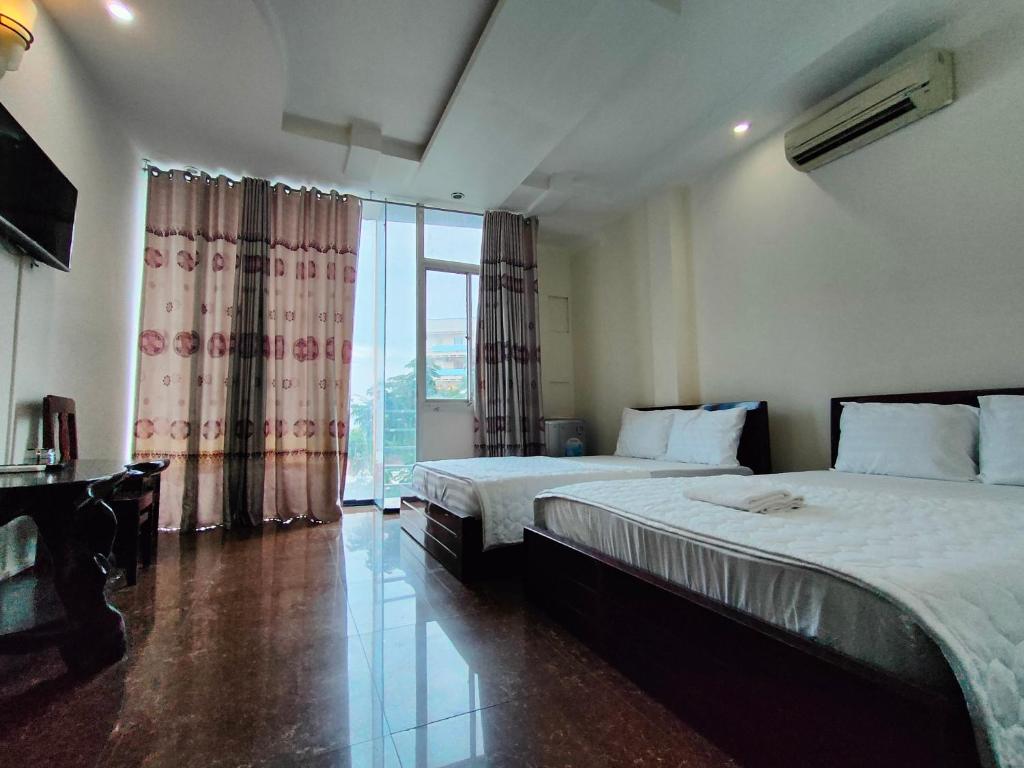 Habitación de hotel con 2 camas y ventana grande. en Khách Sạn Hải Miên, en Ho Chi Minh