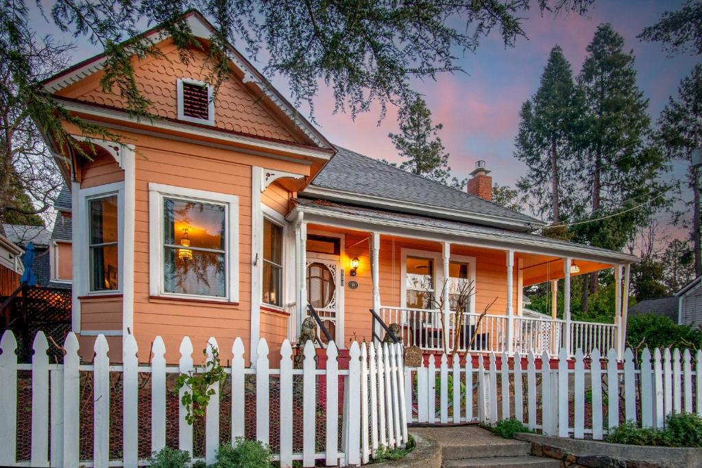 uma pequena casa laranja com uma cerca branca em The Golden Parlor- Historic Victorian, Hot Tub em Grass Valley