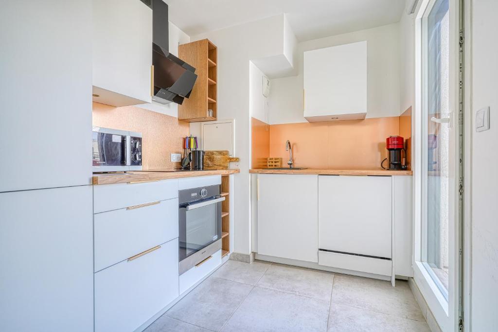 a kitchen with white cabinets and a window at Grand appartement avec belle vue Paris in Rueil-Malmaison