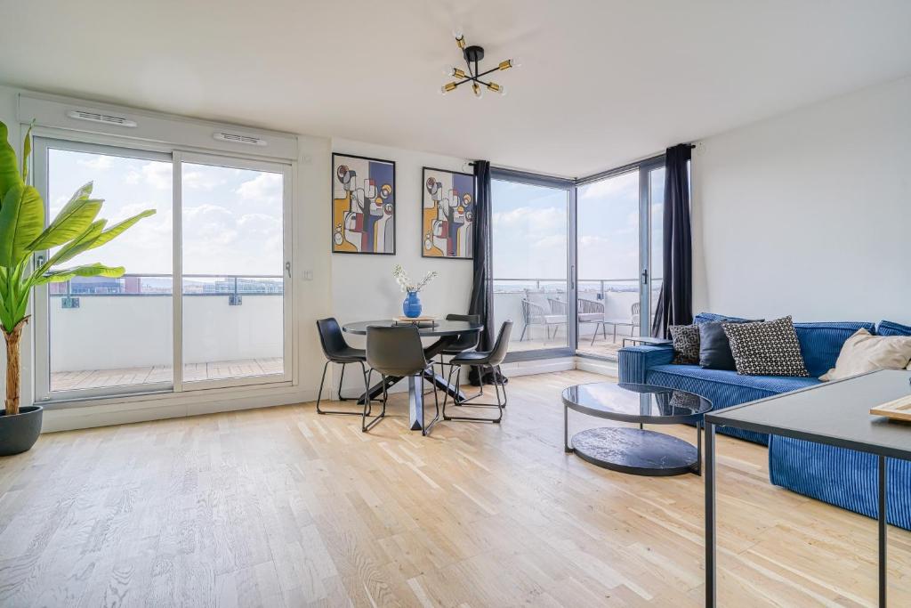 een woonkamer met een blauwe bank en een tafel bij Grand appartement avec belle vue Paris in Rueil-Malmaison