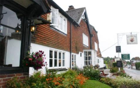 uma grande casa de tijolos com portas e janelas brancas em The Bear Inn and Burwash Motel em Burwash