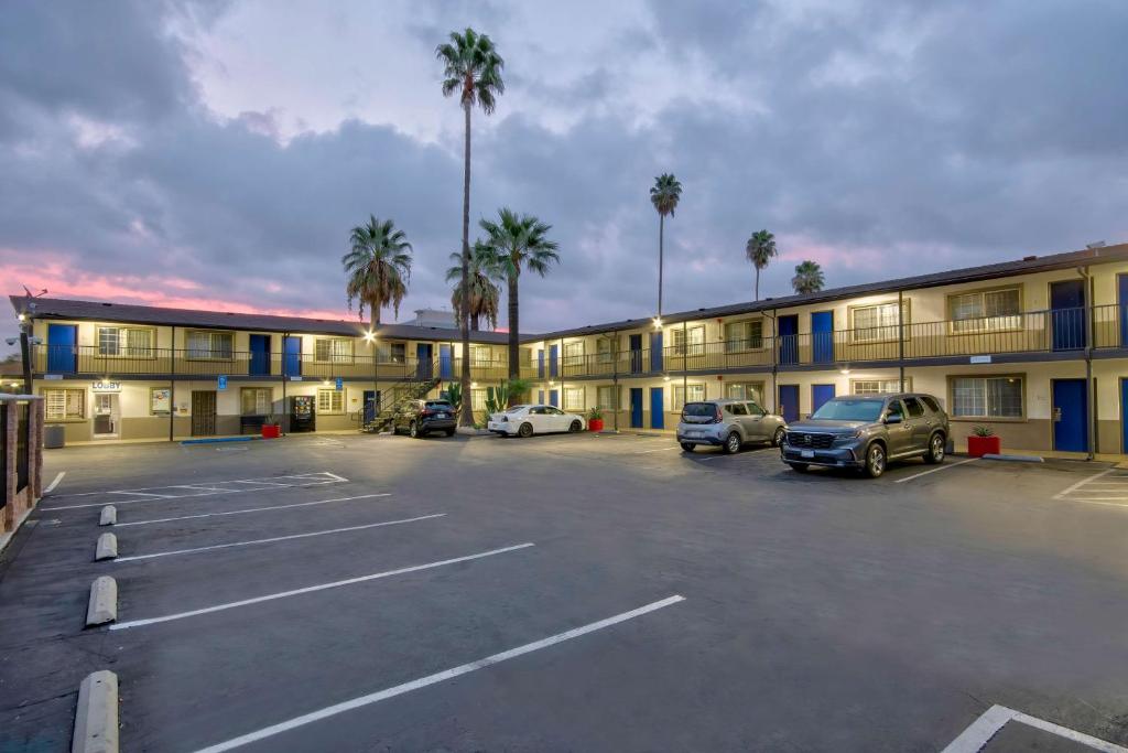 a parking lot in front of a hotel with palm trees at Studio 6 Suites San Bernardino, CA in San Bernardino