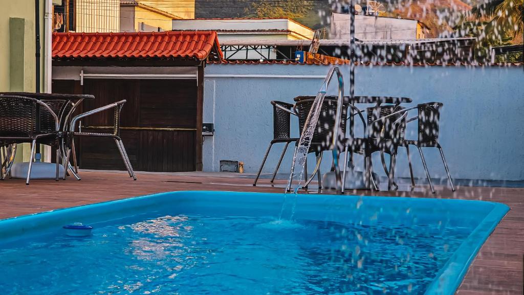 una piscina d'acqua con sedie, tavolo e sedie di Pousada Recanto Praiano ad Angra dos Reis