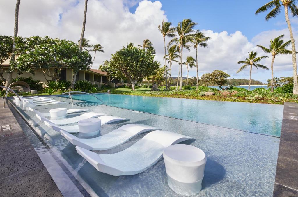 a pool at the resort with white chairs and palm trees at Ocean Bungalows at Turtle Bay Resort in Kahuku