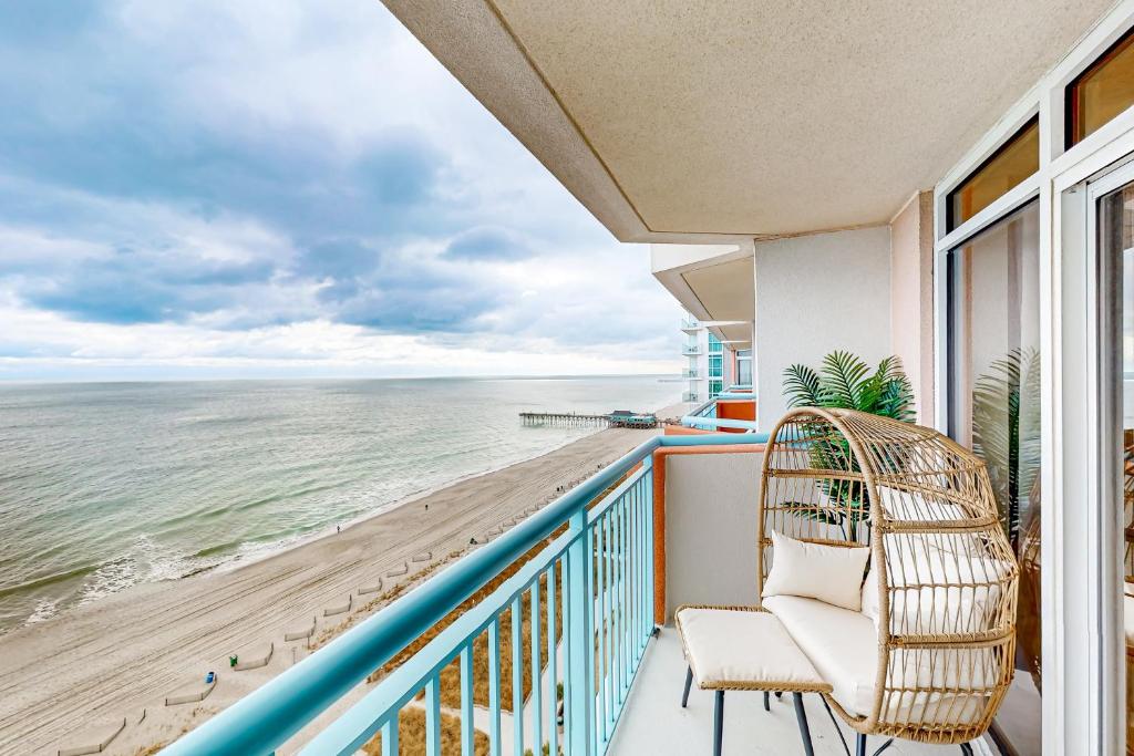 a balcony with a chair and a view of the ocean at Sandy Daydreams, Unit PH3 in Myrtle Beach