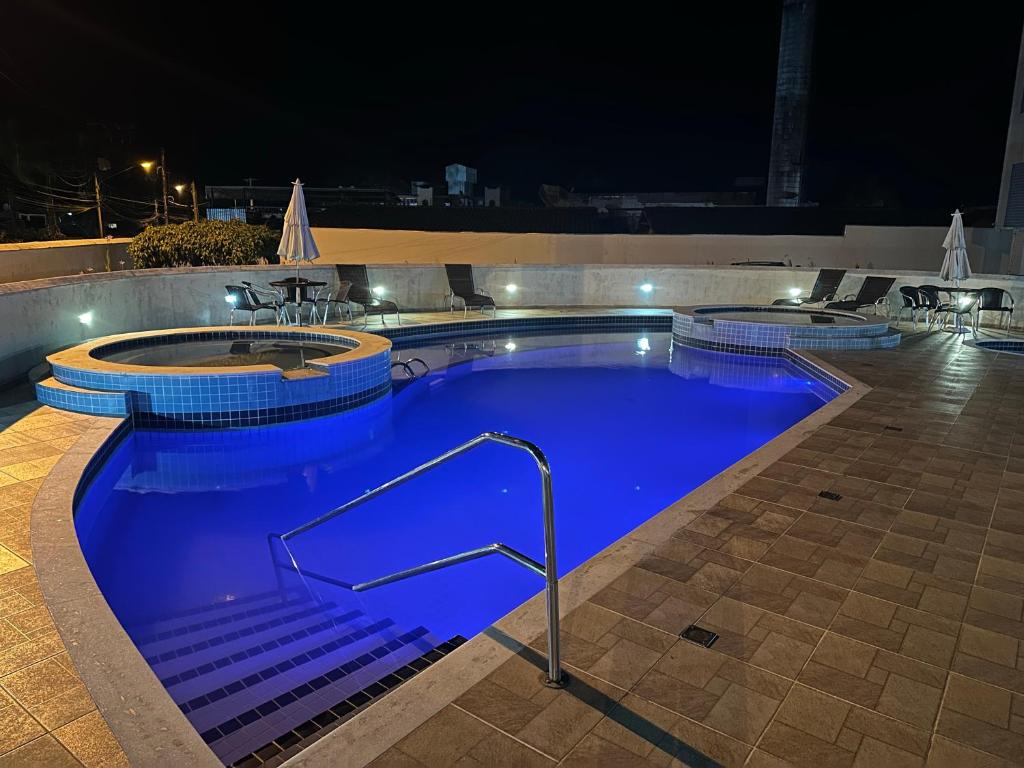 uma grande piscina à noite com água azul em Maravilhosa Cobertura Apto com Vista para o Mar - Praia da Enseada em Ubatuba em Ubatuba