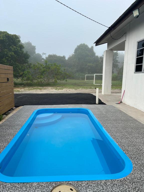 a blue swimming pool in front of a house at Cantik-La Homestay Kolam 3 Bilik Kuala Terengganu in Bukit Payong