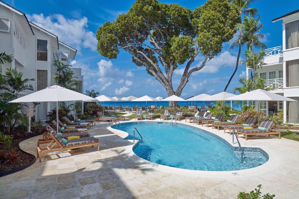 a pool with lounge chairs and umbrellas at a resort at Treasure Beach by Elegant Hotels - All-Inclusive, Adults Only in Saint James