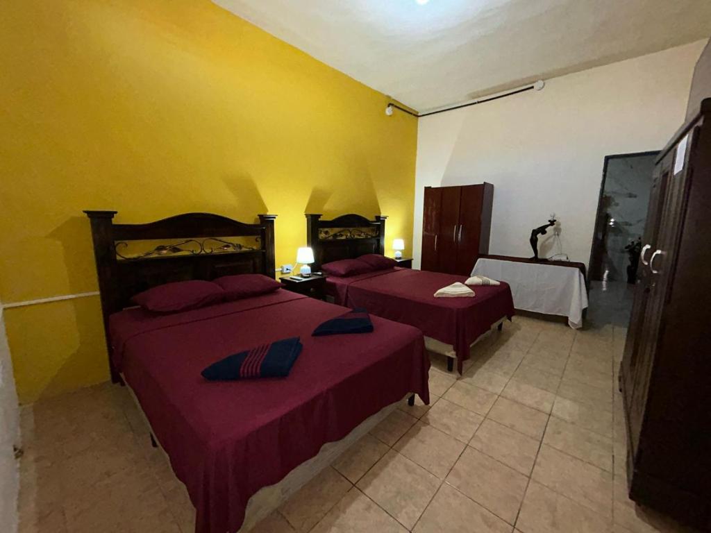 two beds in a room with yellow walls at Casa Maya Itza in Flores