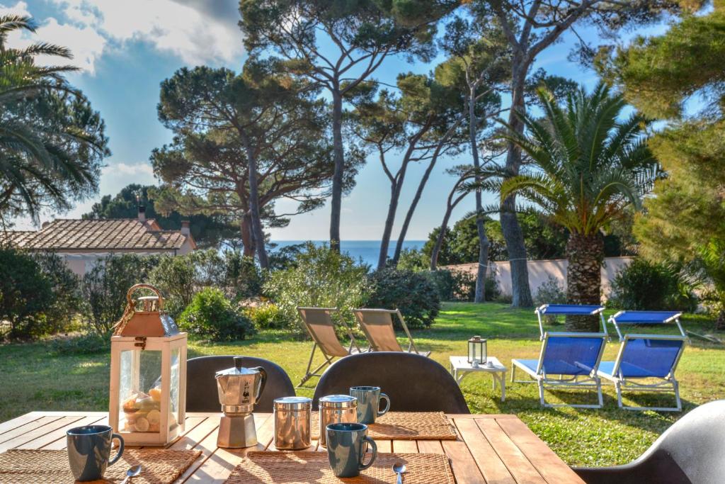 a table with a lantern and chairs and the ocean at Villetta Norsi in Capoliveri