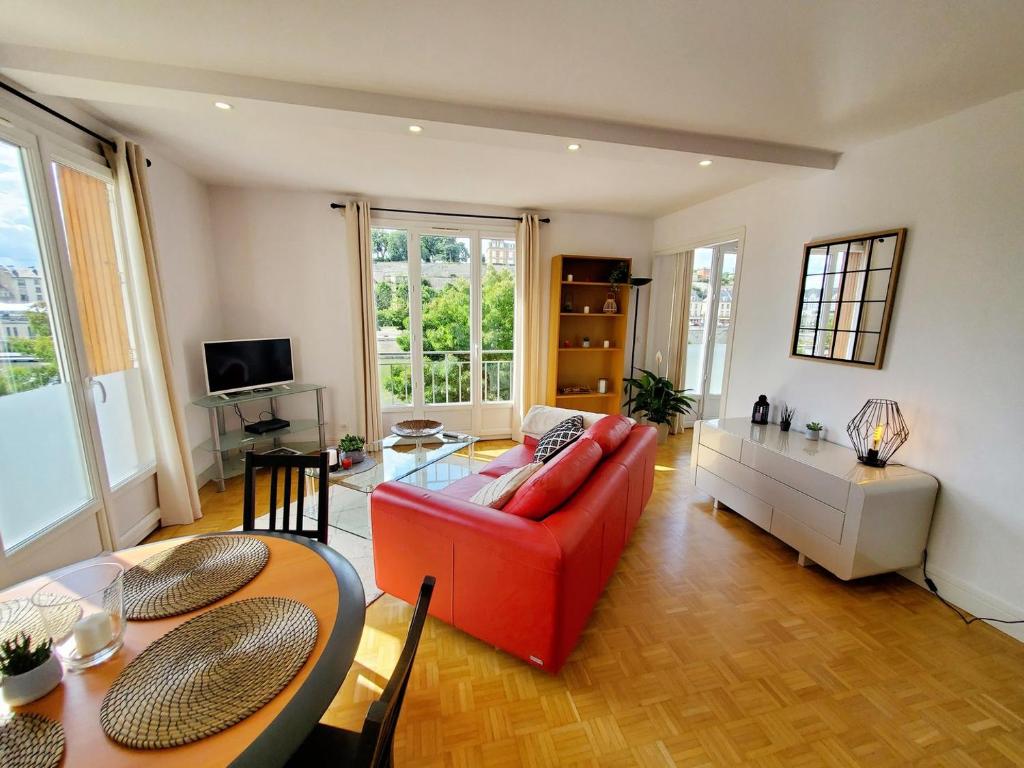 a living room with a red couch and a table at Le Loft de L’Écluse / F2 cosy au bord de l'eau in Pontoise