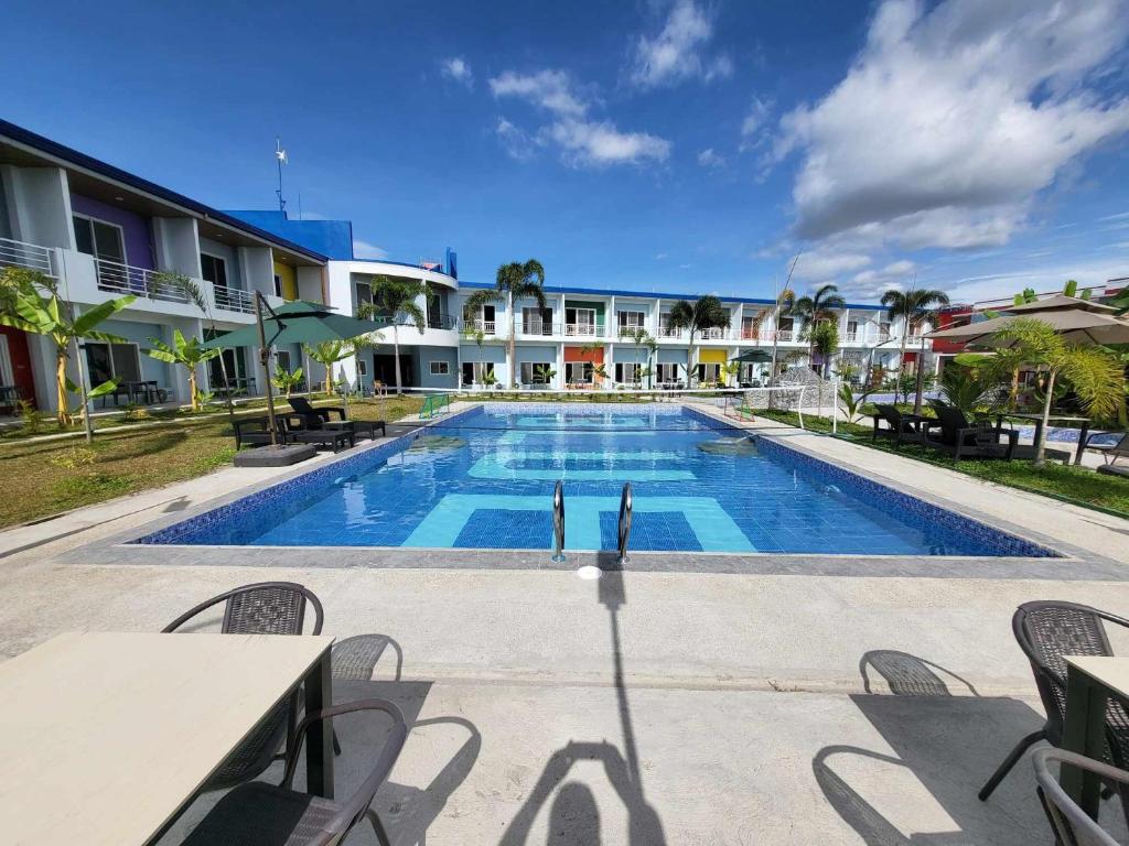 a swimming pool with tables and chairs next to a building at Blue Hotel and Resort in Porac