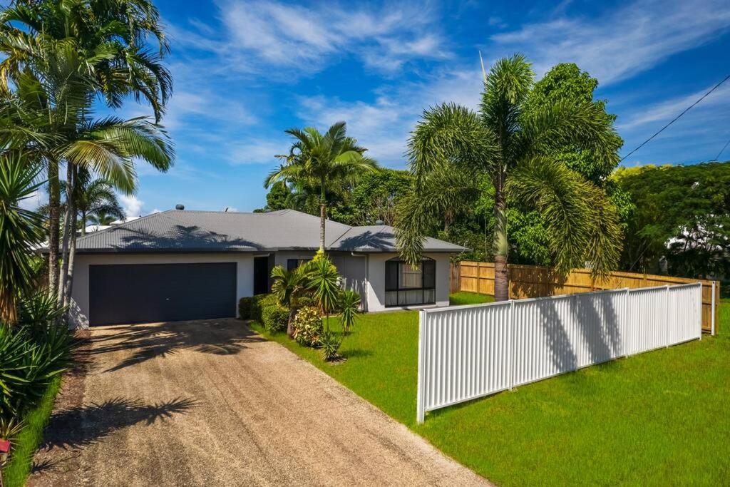 a home with palm trees and a white fence at Spacious Family Fun with SUV Hire, Games, Full Kitchen in Yorkeys Knob