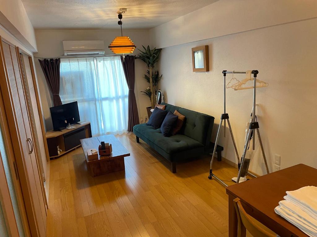 a living room with a green couch and a television at 高原マンション 202 in Horinouchichō