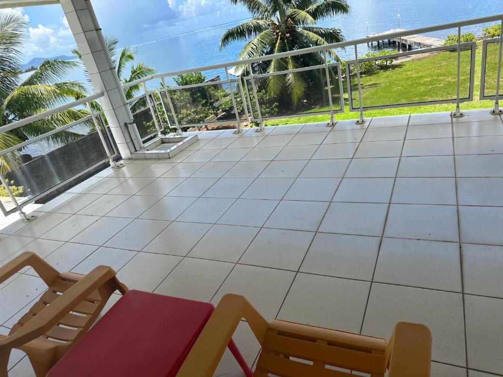 einen Balkon mit einem Tisch, Stühlen und Meerblick in der Unterkunft Chambres bord de mer - raiatea in Uturoa