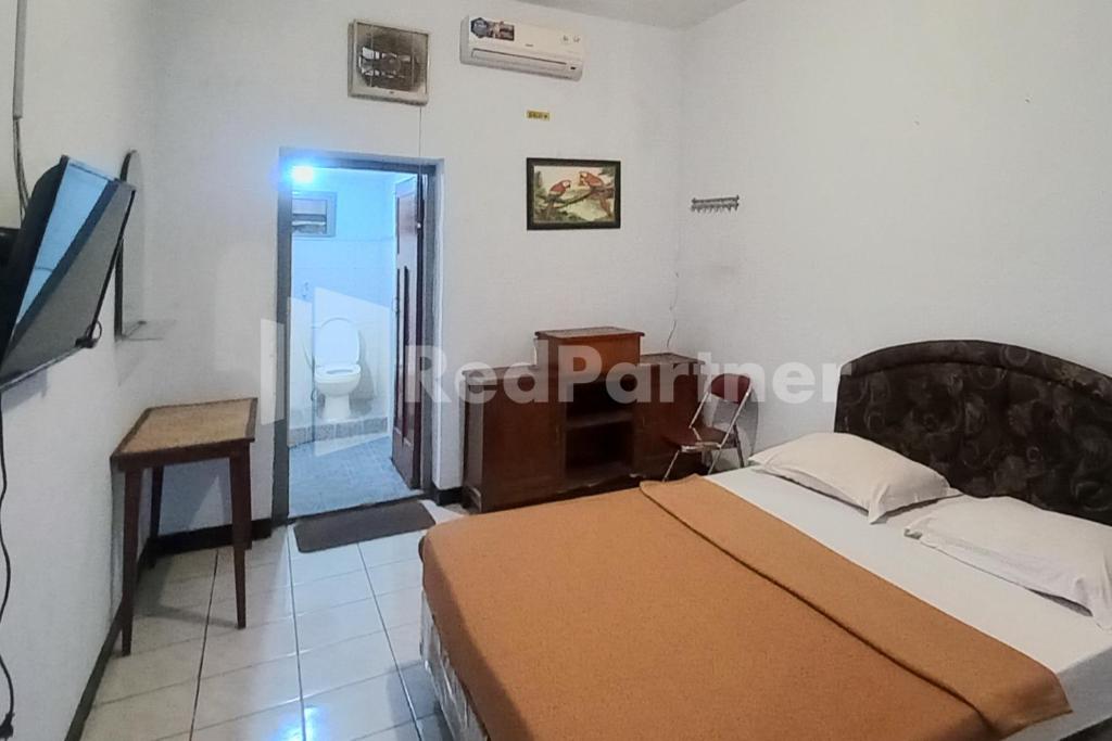 a bedroom with a bed and a television in it at Hotel Palem 1 Syariah RedPartner in Malang