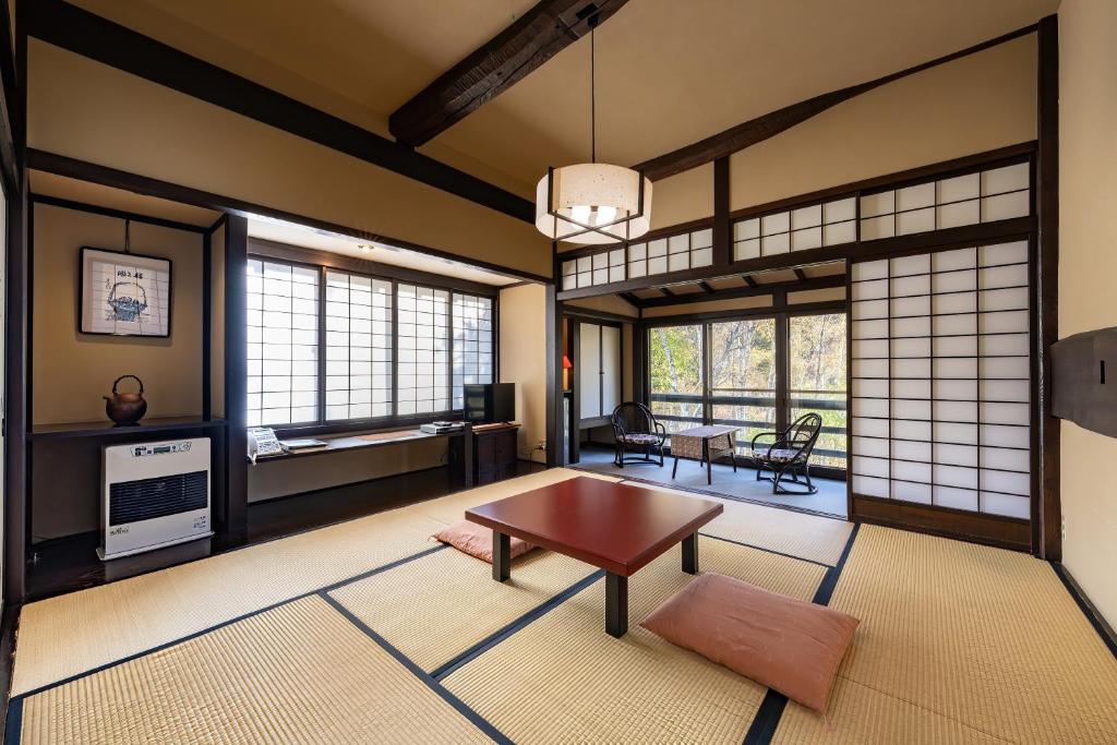 a living room with a table and some windows at Konashi No Yu Sasaya in Matsumoto