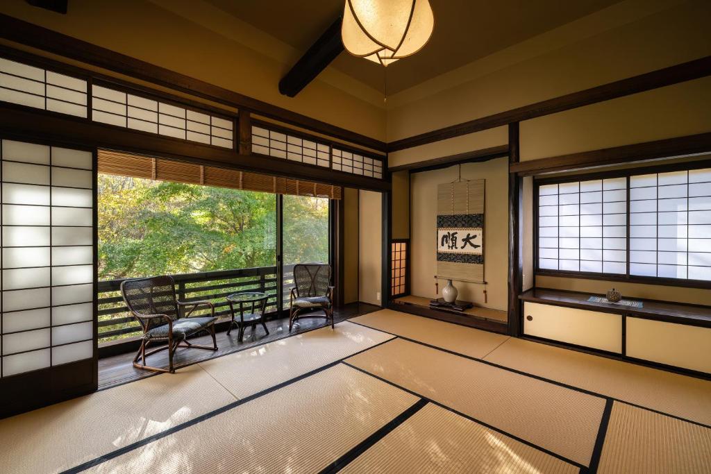 a room with two chairs and a table and windows at Konashi No Yu Sasaya in Matsumoto
