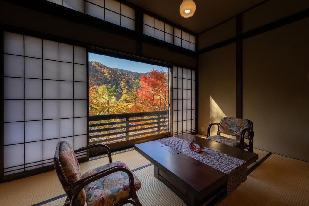 a room with a table and chairs and a large window at Konashi No Yu Sasaya in Matsumoto