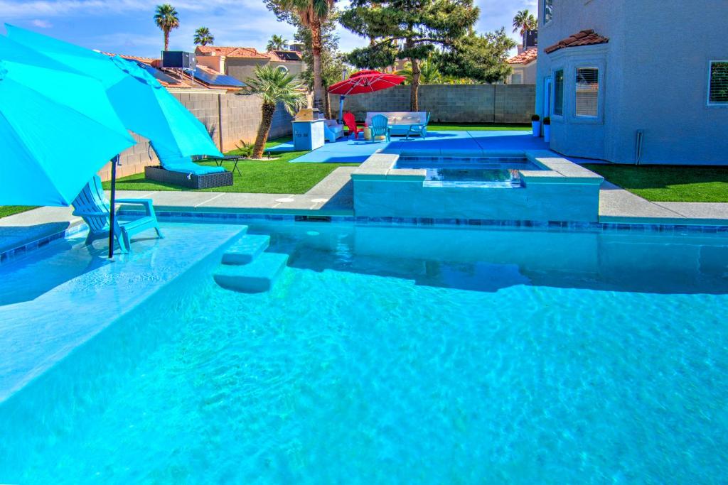 a blue swimming pool with an umbrella in a yard at HOUSE VEGAS in Las Vegas