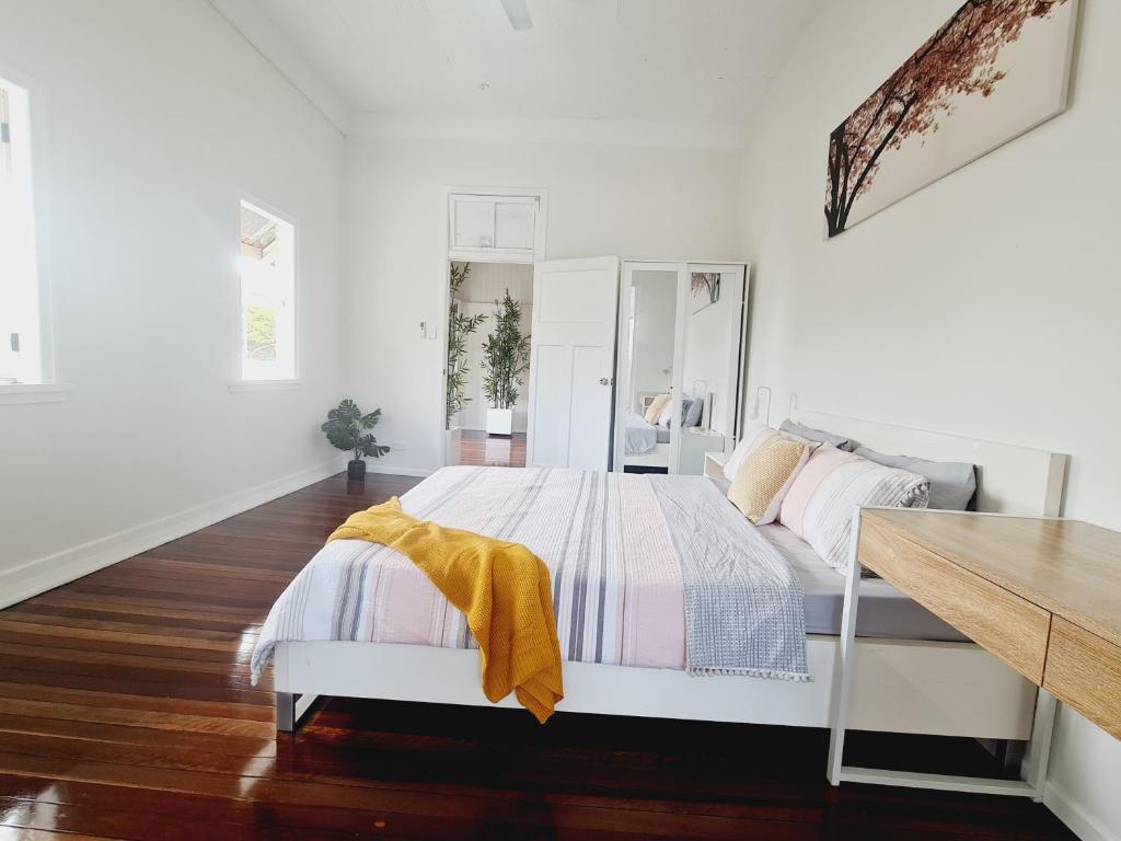 a white bedroom with a bed with a yellow blanket at Exclusive location - Entire 3-bedroom in Maryborough CBD, 10ppl in Maryborough