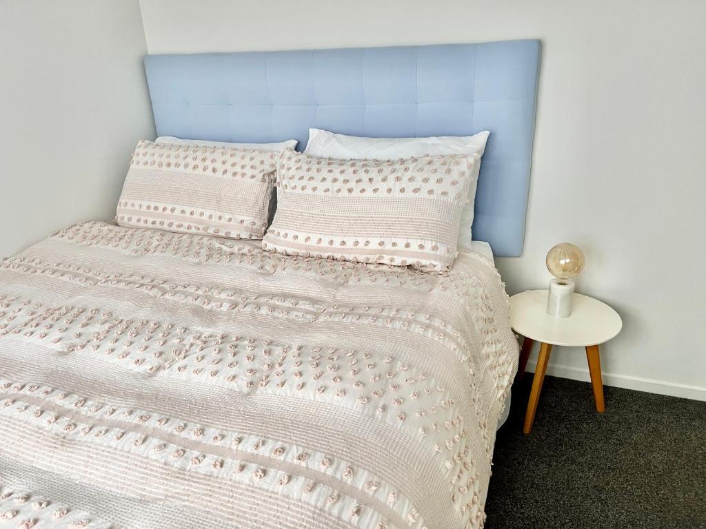 a bedroom with a bed with a blue headboard at House of Somer in Matamata