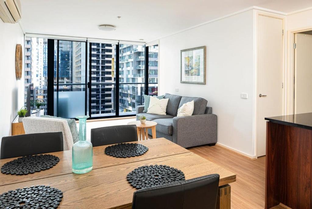 a living room with a table and a couch at Melbourne CBD Apt With A C Balcony & Pool in Melbourne