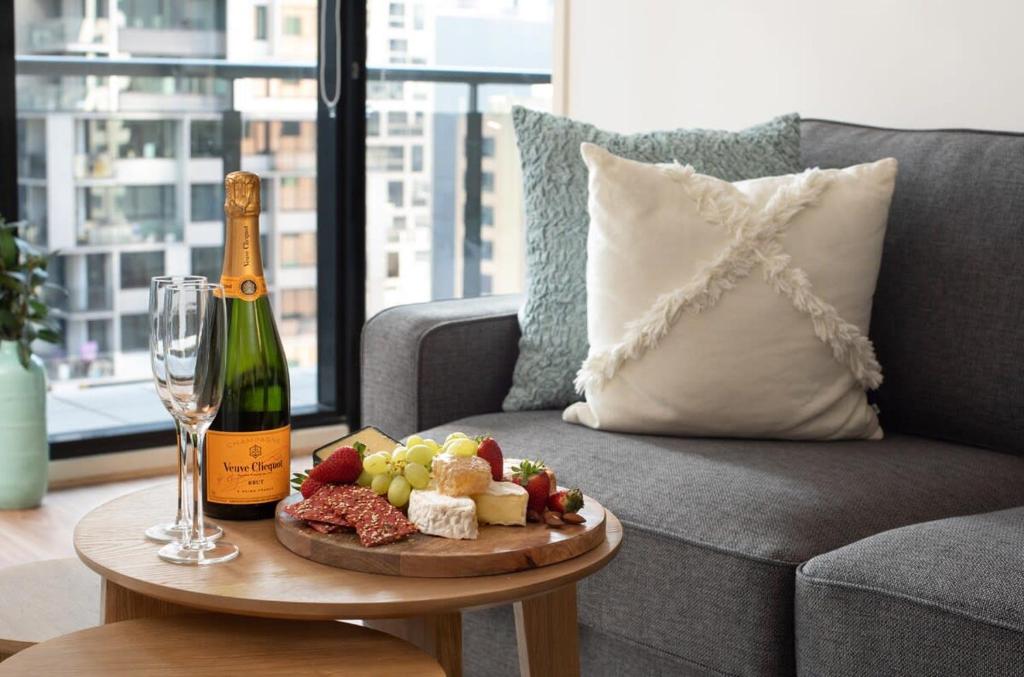 a bottle of champagne and a plate of food on a table at Melbourne CBD Apt With A C Balcony & Pool in Melbourne
