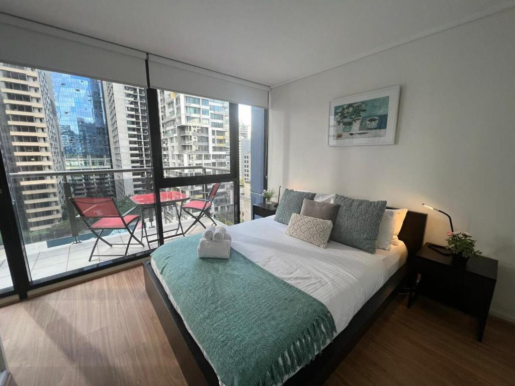 a bedroom with a large bed and a balcony at Melbourne CBD Apt With A C Balcony & Pool in Melbourne