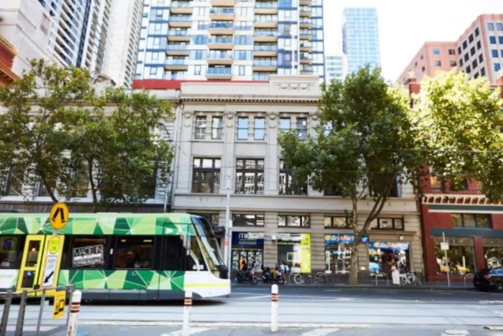 a bus driving down a street in a city at Melbourne CBD Apt With A C Balcony & Pool in Melbourne