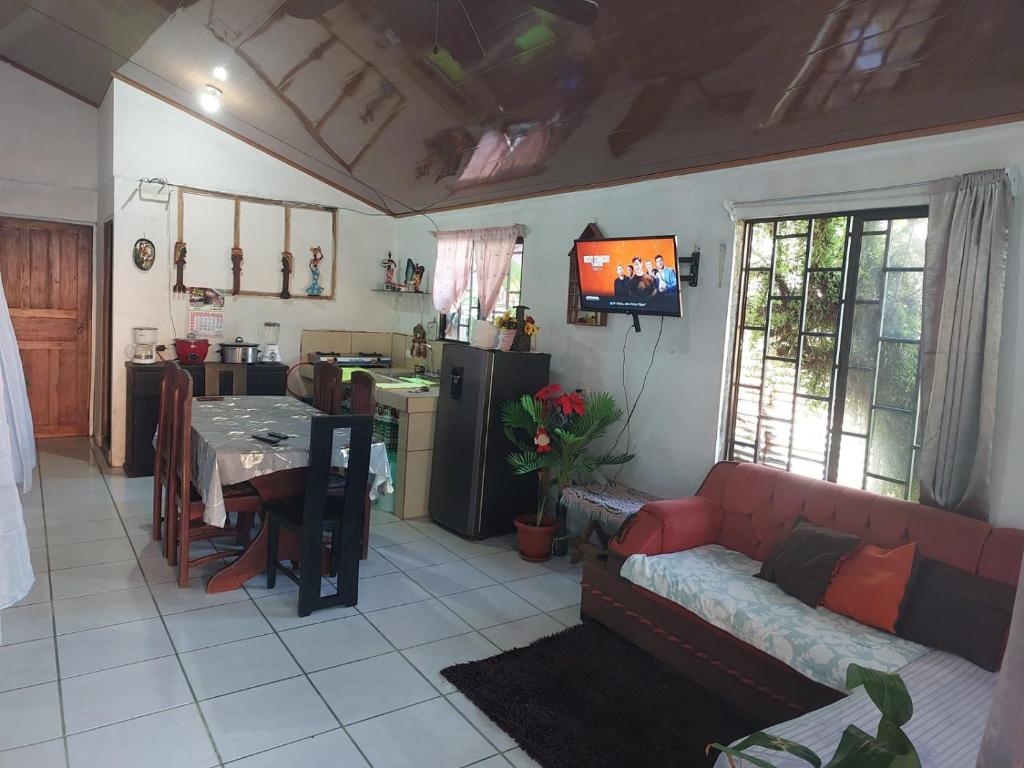 a living room with a red couch and a kitchen at Tortuguero family house hostel in Tortuguero