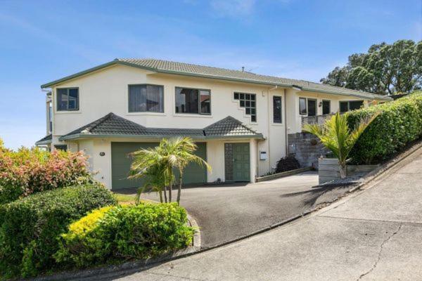 a large white house with palm trees and bushes at panoramic vista with sea views in New Plymouth