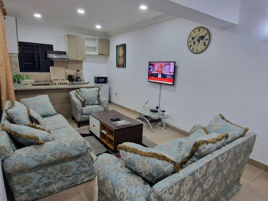 阿布賈的住宿－Stylish & Comfy 1 Bedroom Apt，客厅设有两张沙发和墙上的时钟