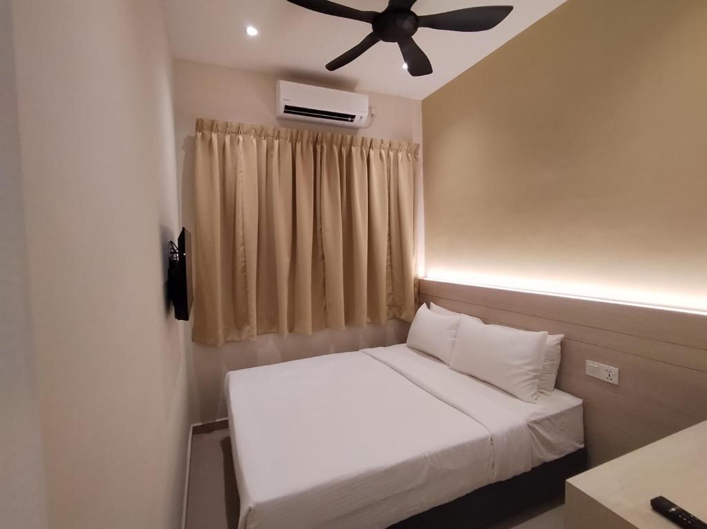 een slaapkamer met een wit bed en een plafondventilator bij Eighteen Guesthouse in Kuantan