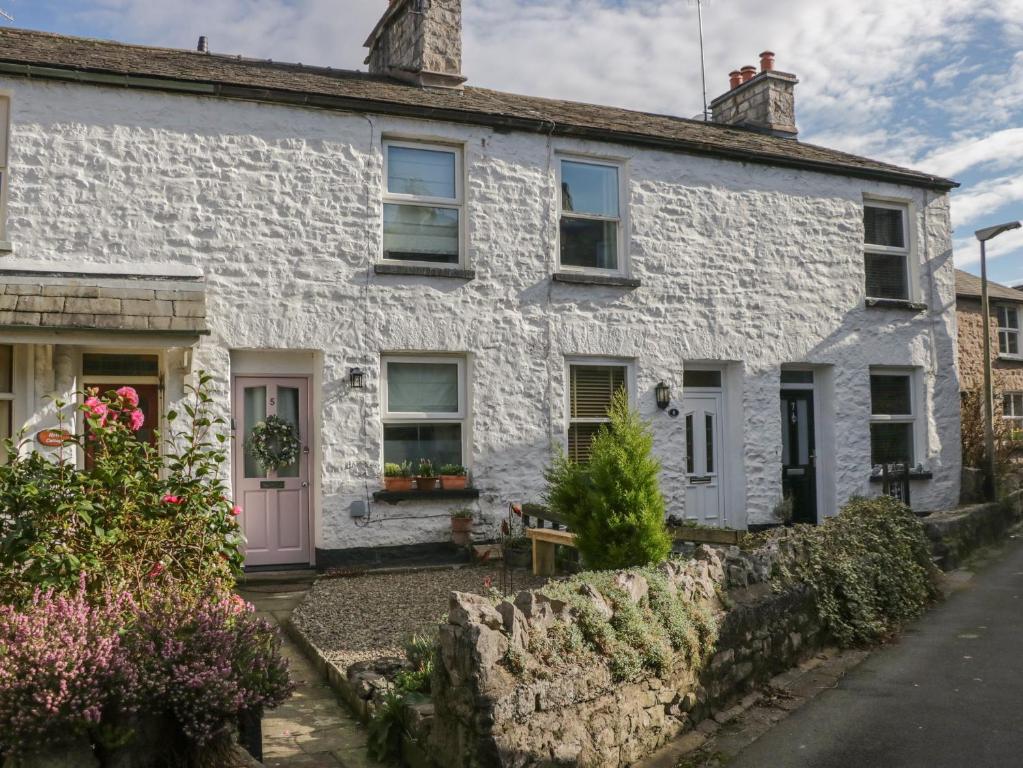 ein weißes Haus mit einer rosa Tür und Blumen in der Unterkunft Gosling Cottage in Kendal